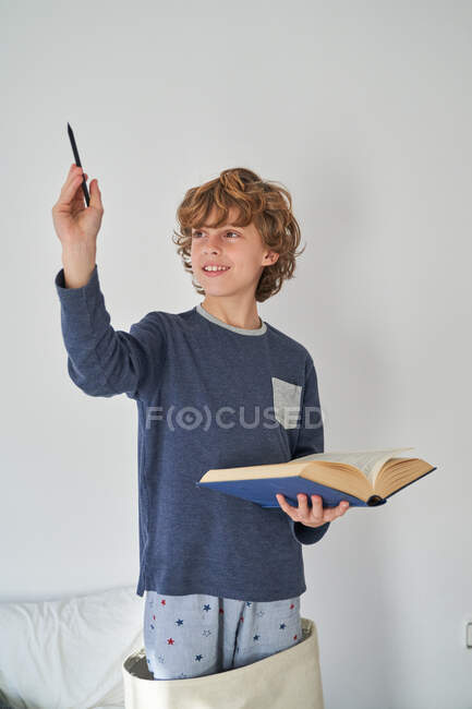Criança loira de pijama com um livro jogando pesquisa — Fotografia de Stock