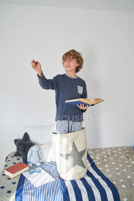 Niño rubio en pijama con un libro jugando a la investigación - foto de stock