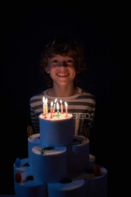 Blond boy blowing out the candles on his toilet paper birthday cake — Stock Photo