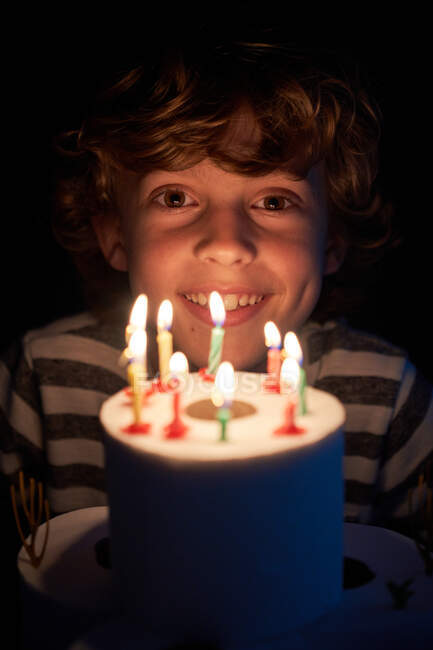 Rubio chico soplando las velas en su papel higiénico pastel de cumpleaños - foto de stock