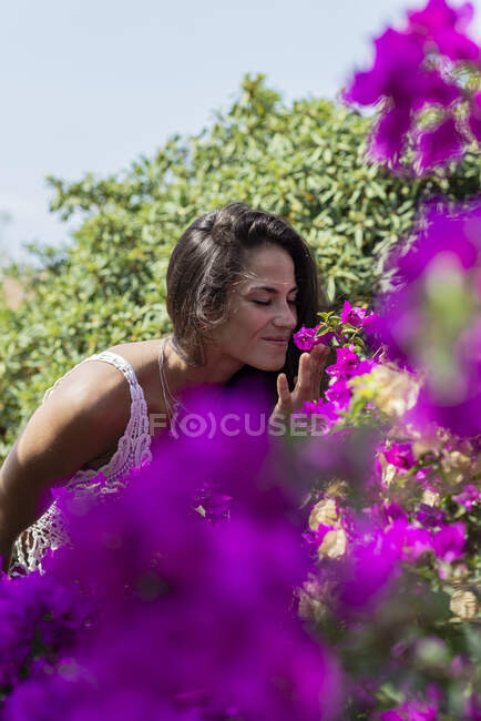 Молодая красивая женщина нюхает цветок в саду — стоковое фото