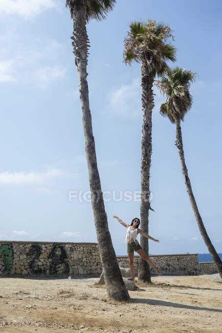 Young hispanic woman on dancing between palm trees — Stock Photo