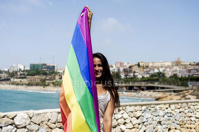 Retrato de una mujer hispana envuelta alrededor de una bandera lgtb - foto de stock