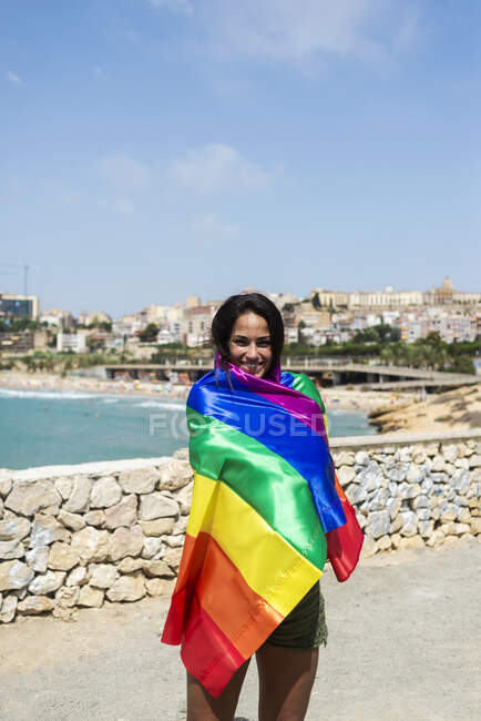 Portrait d'une jolie femme hispanique enroulée autour d'un drapeau lgtb — Photo de stock