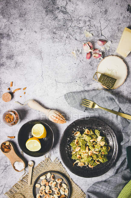 From above portion of delicious roasted green broccoli with almonds on black plate on gray table in composition with different ingredients for preparing dish at home — Stock Photo