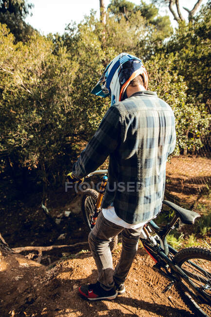 Sportif vététiste méconnaissable debout au sommet d'une colline en forêt — Photo de stock