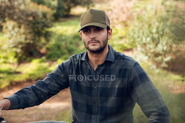 Mountain biking sportsman without protection sitting on bike in the middle of a forest looking away — Stock Photo