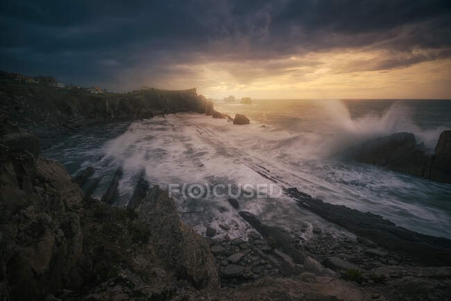 Magnífica paisagem de costa rochosa e ondas de espuma oceânica perturbadas durante o pôr do sol — Fotografia de Stock