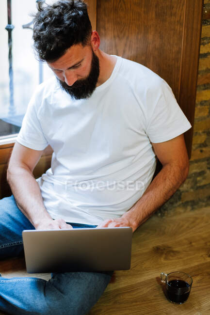 Бородатий фрілансер використовує ноутбук вдома — стокове фото