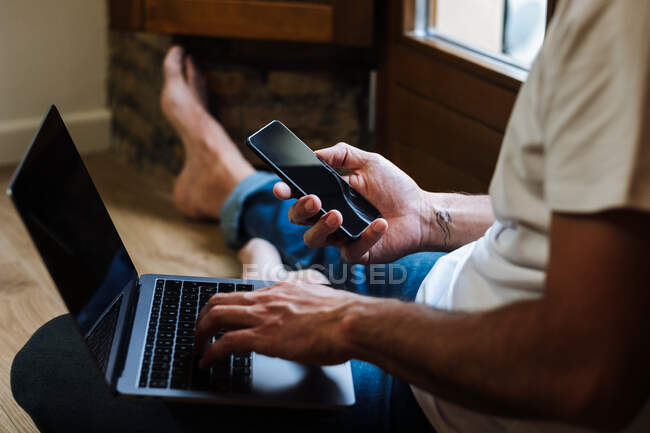Crop freelancer with laptop and smartphone — Stock Photo
