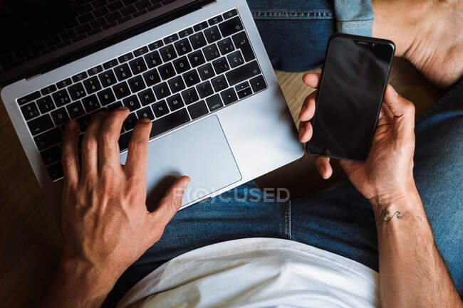 Кроп фрилансер с ноутбуком и смартфоном — стоковое фото