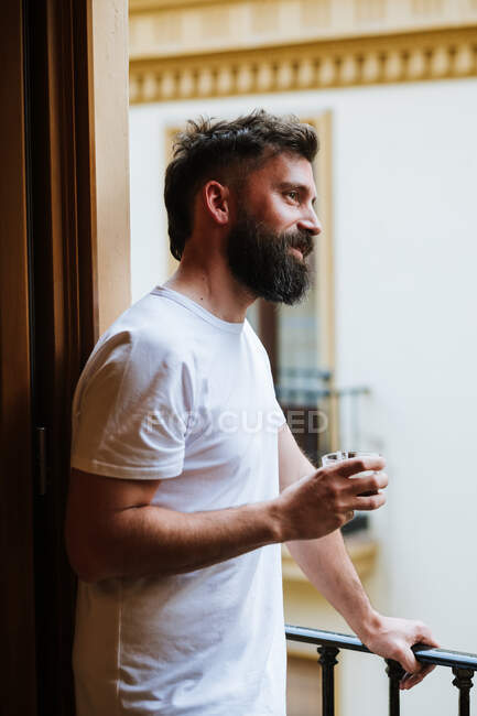 Bearded guy with hot drink resting on balcony — Stock Photo