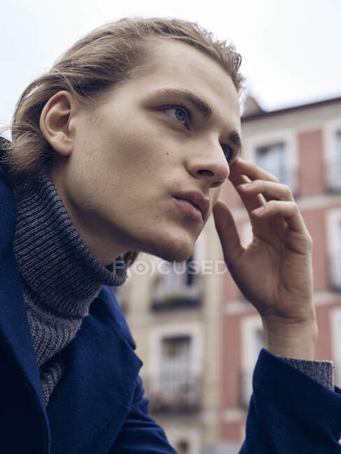 Seitenansicht des stilvollen jungen Mannes mit trendiger Frisur in elegantem Mantel, der in der Stadt steht — Stockfoto