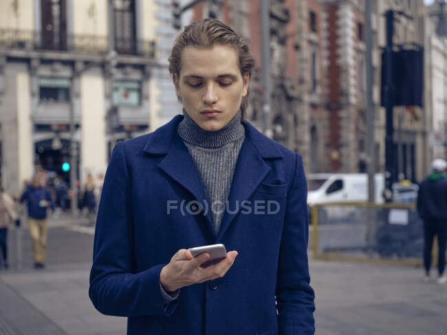 Jeune homme élégant naviguant sur smartphone dans la rue sur la rue de la ville — Photo de stock