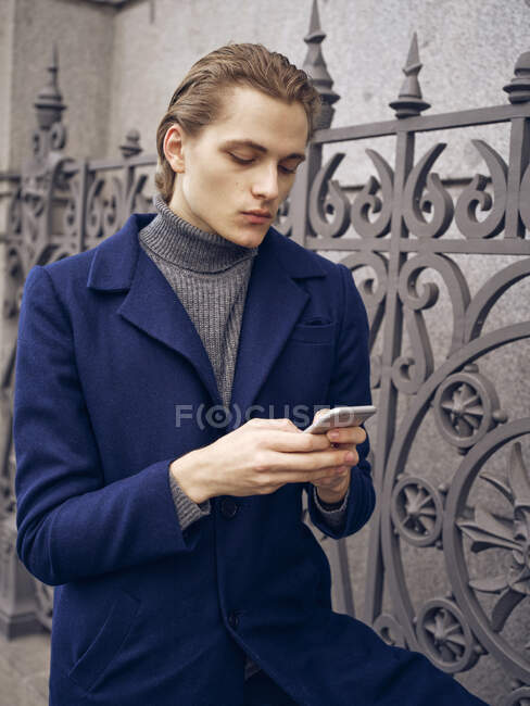 Stylish young man browsing on smartphone on street on city street — Stock Photo