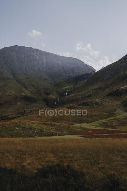 Paesaggio tranquillo della campagna scozzese con prati gialli in montagna rocciosa contro il cielo nuvoloso — Foto stock