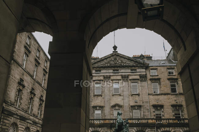 Low angle of old building of Edinburgh City Chambers with statue in yard seen from under arch — Stock Photo