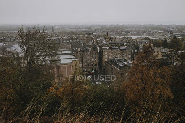 Desde arriba paisaje urbano de la vieja ciudad de Edimburgo con edificios de piedra bajo el cielo gris brumoso en el día de otoño - foto de stock