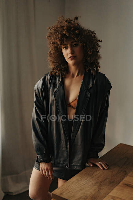 Mulher sensual em jaqueta de couro e sutiã com cabelo encaracolado no quarto — Fotografia de Stock