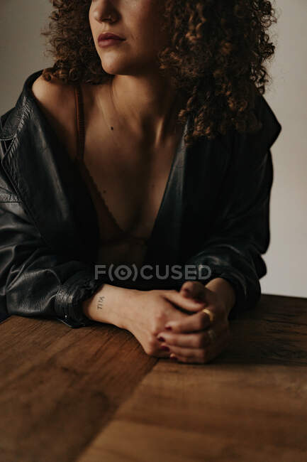 Mujer sensual en chaqueta de cuero y sujetador con pelo rizado en la habitación - foto de stock