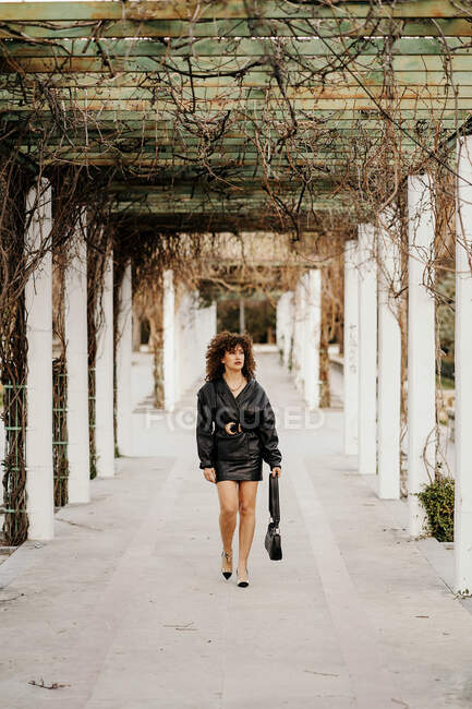 Feminino gerente em terno saia de couro preto olhando embora enquanto caminha — Fotografia de Stock