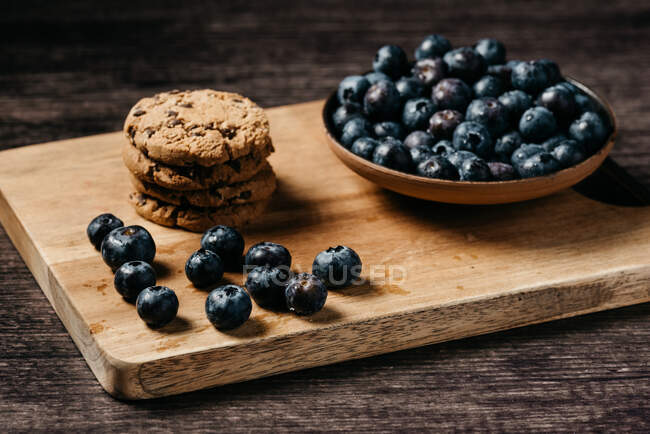 Mirtilo e biscoitos em tábua de madeira — Fotografia de Stock