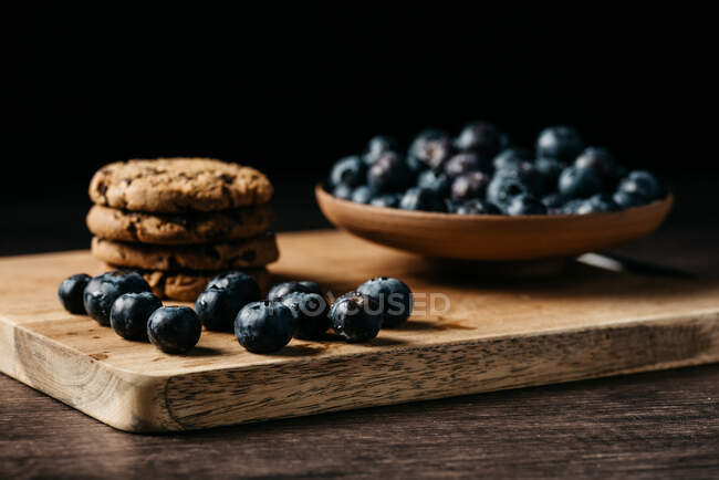Mirtilo e biscoitos em tábua de madeira — Fotografia de Stock