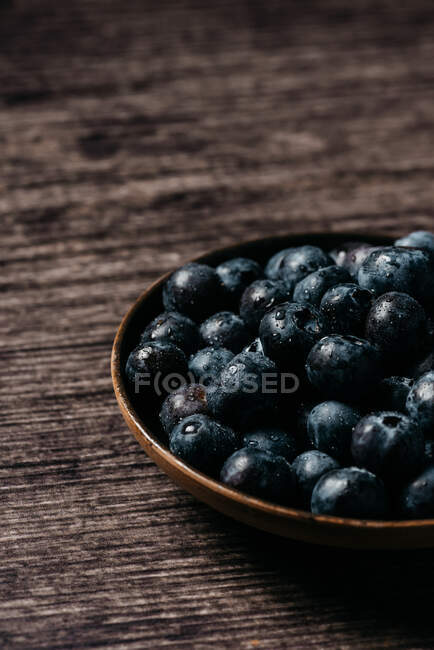 Fresh blueberries on wooden bowl on table — Stock Photo