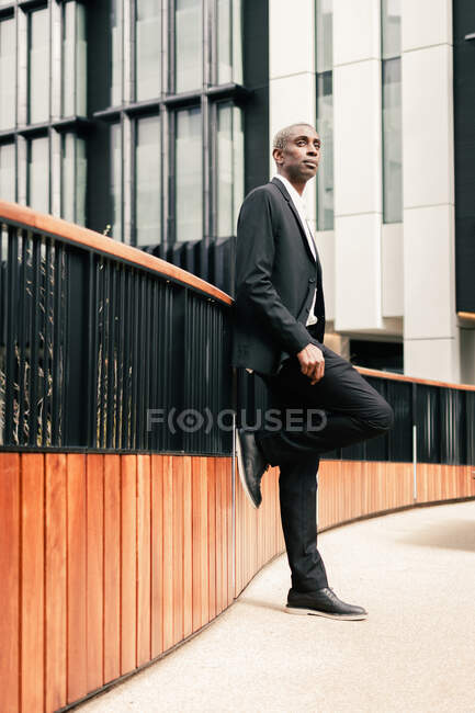 Homme d'affaires noir confiant penché sur la rampe — Photo de stock
