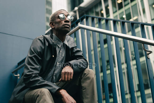 Стильний чорний чоловік сидить на гастролях на вулиці — стокове фото