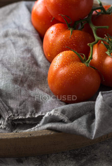 From above of wet clean tomatoes placed on gray fabric napkin on grey concrete table background — Stock Photo