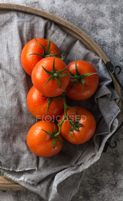 Desde arriba vista superior de tomates limpios húmedos colocados en servilleta de tela gris sobre fondo de mesa de hormigón gris - foto de stock