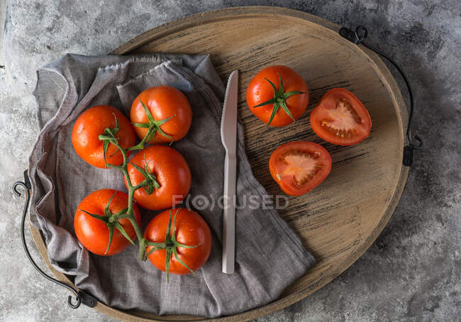 Halbierte und ganze frische Tomaten während der Zubereitung in der Küche auf einen groben grauen Tisch gelegt — Stockfoto