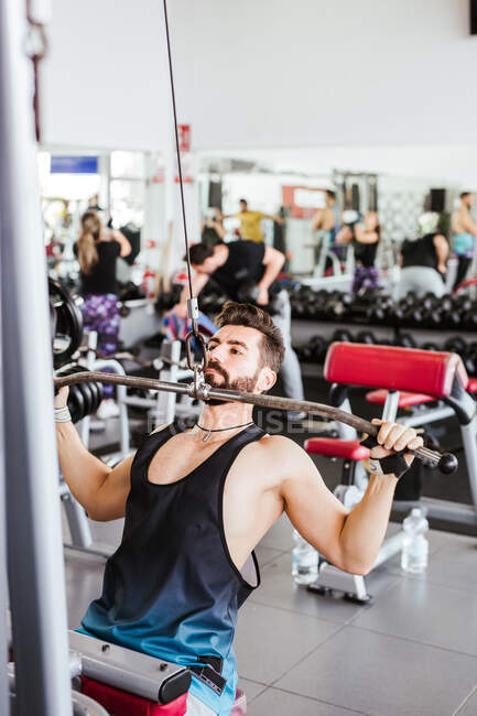 Esportista determinado poderoso fazendo exercício com barra no rack de agachamento durante o treinamento de levantamento de peso com treinador pessoal no ginásio moderno — Fotografia de Stock