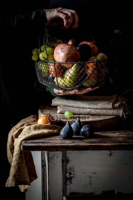Crop senior person taking fruit from basket — Stock Photo