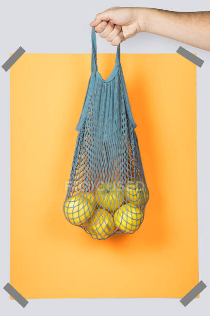 Borsa a mano a rete irriconoscibile con mele mature contro il rettangolo arancione durante lo shopping a zero rifiuti — Foto stock