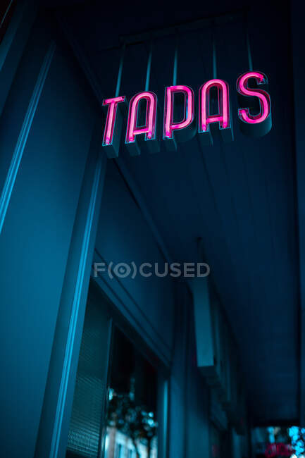 Von unten hängt abends ein rosafarbenes Tapas-Schild vor dem Diner auf der Stadtstraße — Stockfoto