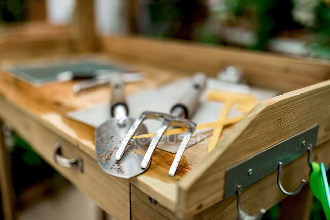 From above blurred various gardening instruments placed on lumber table in hothouse — Stock Photo
