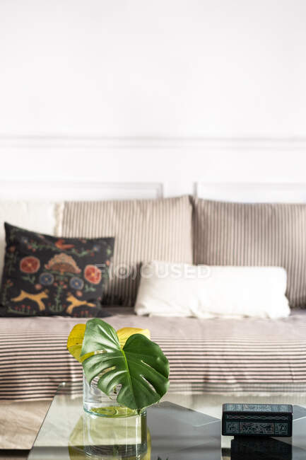 Cómodo sofá con cojines suaves cerca de mesas con decoraciones en la acogedora sala de estar con estilo en casa - foto de stock