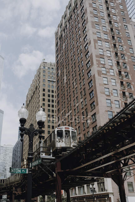 Bajo ángulo de la calle de la ciudad de Chicago con el tren de cercanías que va en vía elevada cerca de edificios modernos de alta - foto de stock