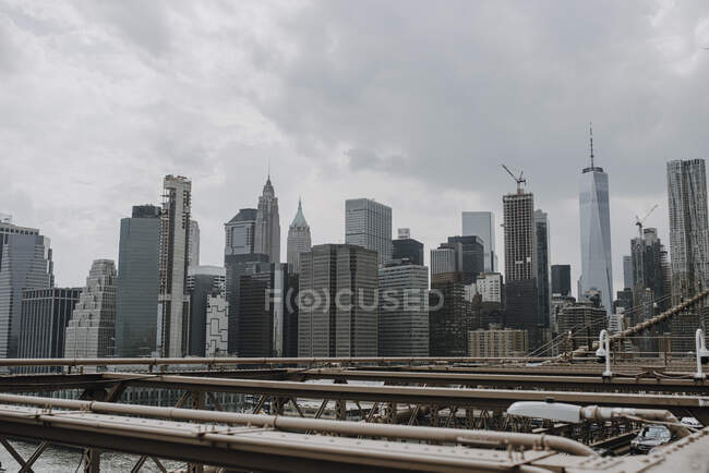 New York City skyline with modern skyscrapers seen from bridge over river in cloudy summer day — Stock Photo