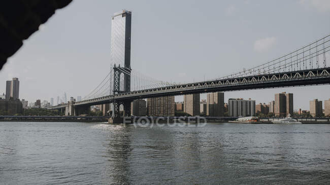 Modern cityscape with bridge over river in evening — Stock Photo