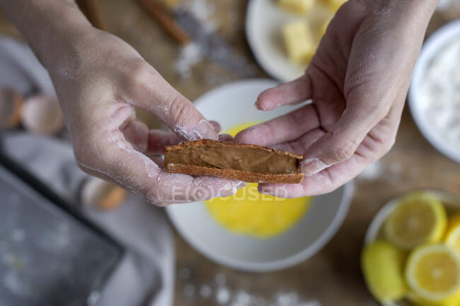 Dall'alto vista della donna anonima delle colture che mostra la cannella sul tavolo di legno con burro di farina e ingredienti di limone per la torta sullo sfondo — Foto stock