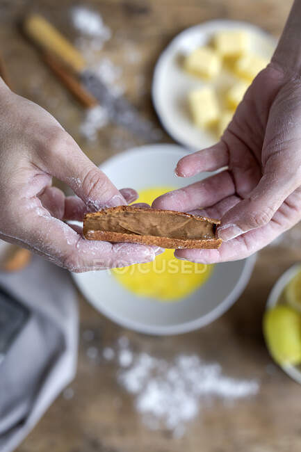 From above top view of crop anonymous woman showing cinnamon on wooden table with flour butter and lemon ingredients for cake on the background — Stock Photo