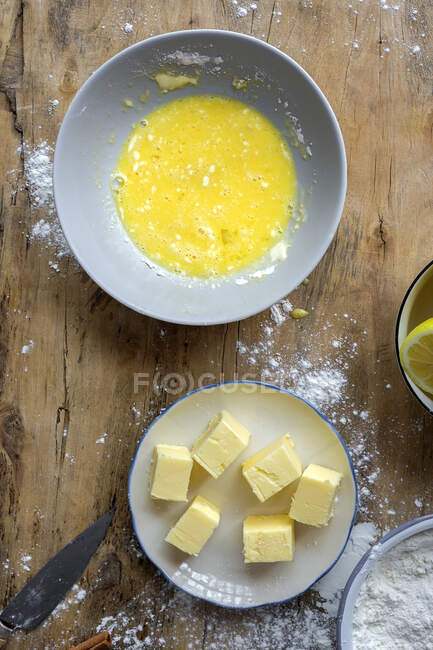Vista dall'alto degli ingredienti per la ricetta della torta tra cui ciotola con farina e uovo posto sul tavolo di legno spolverato — Foto stock