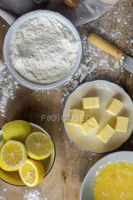 Top view of ingredients for cake recipe including bowl with flour and egg placed on dusted wooden table — Stock Photo