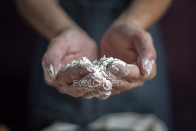 Cultivé femme méconnaissable montrant les mains pleines de farine près bol noir tout en préparant la pâtisserie à la maison — Photo de stock