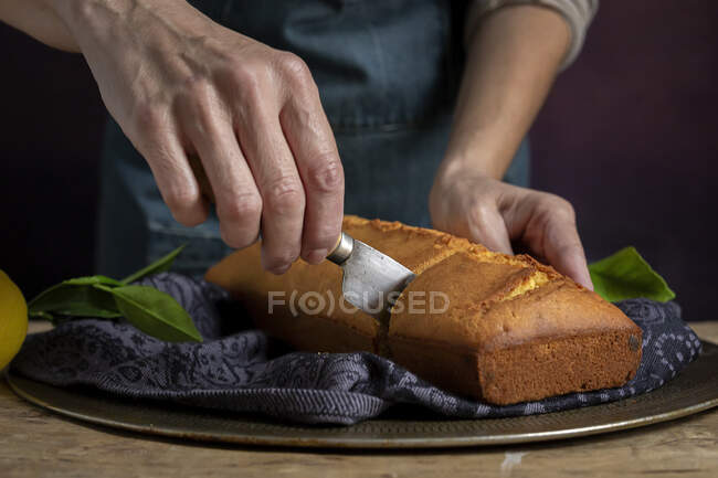 Coupé les mains de femme méconnaissable couper en deux avec un couteau un gâteau au citron fait maison — Photo de stock