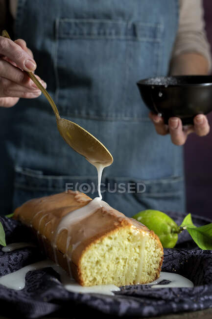 Сверху обрезанные неузнаваемые женские руки льют белую глазурь на домашний лимонный торт — стоковое фото