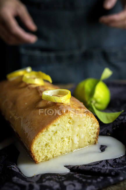 Cropped unrecognizable woman hands preparing a homemade delicious lemon cake covered with glaze and lemon slices — Stock Photo